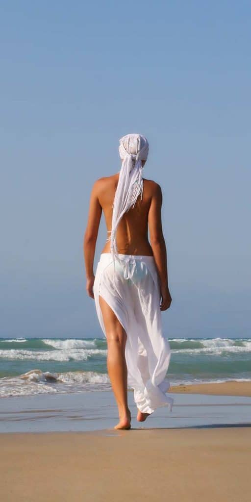 woman walking towards the water at hidden beach - Castaways Travel
