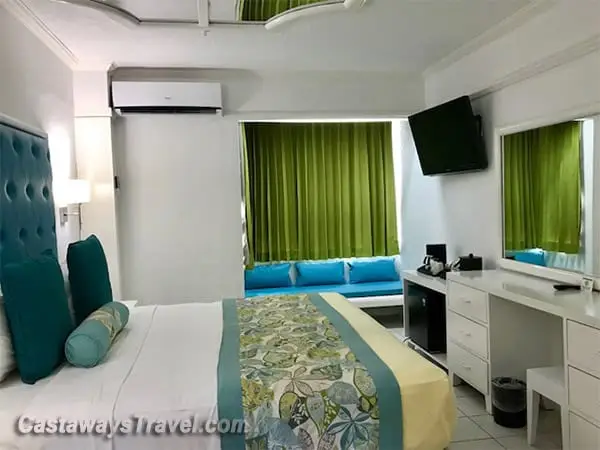 Classic room at Hedonism II Resort in Negril Jamaica featuring a king bed, teal accents, and modern furnishings
