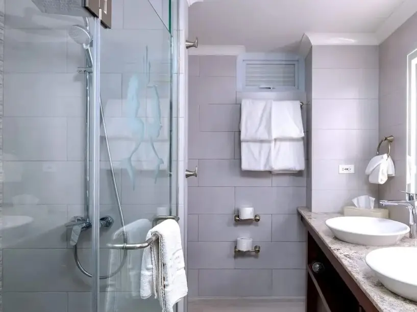 Modern premium bathroom at Hedonism II resort in Negril Jamaica featuring glass shower double sinks and illuminated mirrors