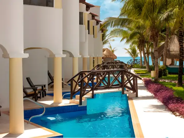 Oceanfront swim-up suites with bridges over a lagoon-style pool at Hidden Beach Riviera Maya, Mexico, during a nude hotel takeover event.