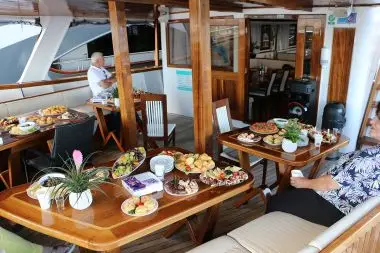 Outdoor dining deck on the MV Majestic prepared with fresh Mediterranean appetizers and local wine, offering open-air meals and relaxed social time during the Southern European Naturist Nude Cruise.