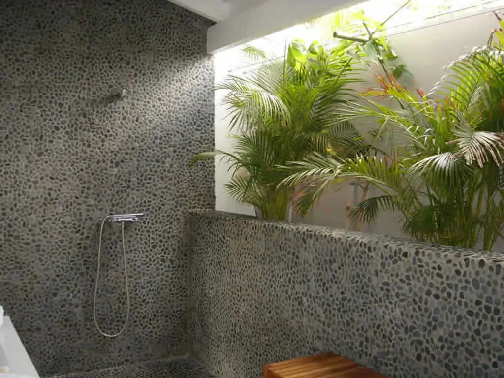 Open-air pebble stone shower surrounded by tropical plants at Le Cottage, a nude clothing optional Caribbean adult-only resort