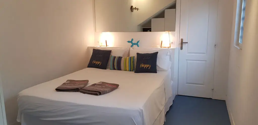 Cozy Caribbean adult-only resort bedroom with white linens, navy blue pillows, and cheerful modern decor inside Studio Indigo