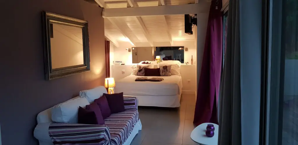Stylish Caribbean adult-only resort studio with plush white bed, purple accent pillows, and cozy lighting inside Studio Purple