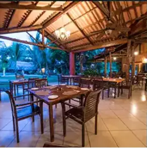 Open-air restaurant and dining area with wooden tables overlooking tropical gardens at a clothing optional resort in Panama