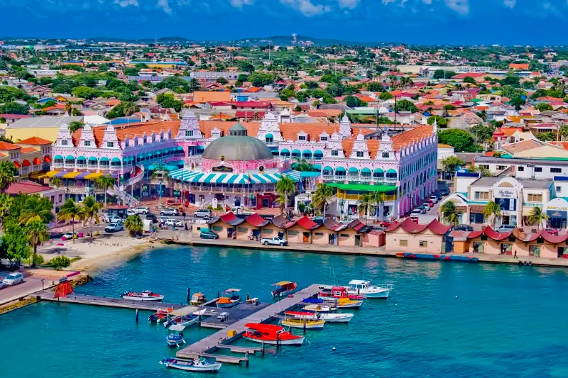 Colorful waterfront houses and marina in Oranjestad Aruba, a port of call on Bliss Cruise Wonder of the Seas November 2026