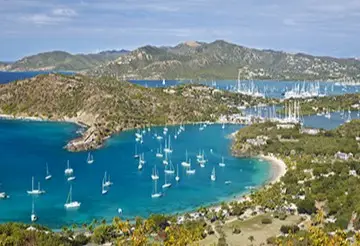 Aerial view of Antigua’s harbor with sailboats anchored near lush hills