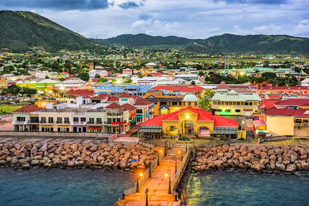 Vibrant waterfront view of Basseterre, St. Kitts & Nevis, a popular Caribbean destination for swinger cruise couples only, featuring colorful buildings, lush hills, and scenic ocean views.