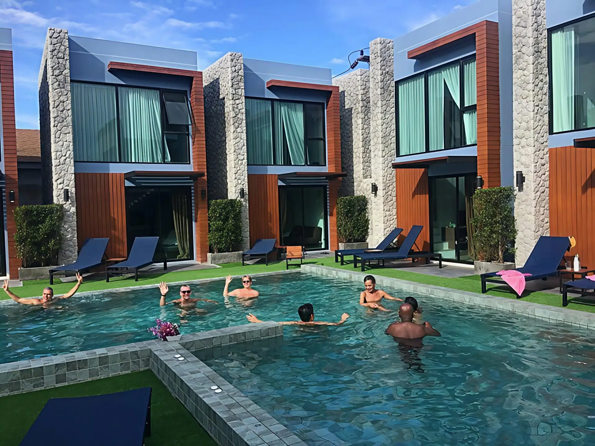 Guests enjoying the pool at Peace Blue Naturist Resort in Phuket Thailand, surrounded by modern nude-friendly pool villas.