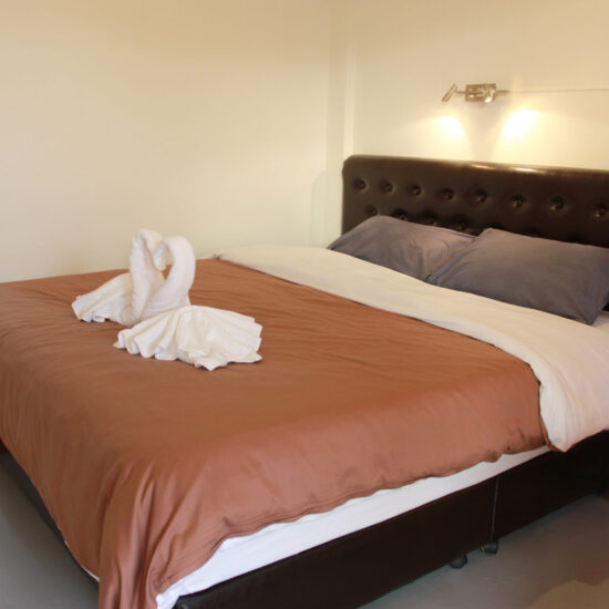 Bright bedroom with king bed and towel swan decoration at Barefeet Naturist Resort in Bangkok