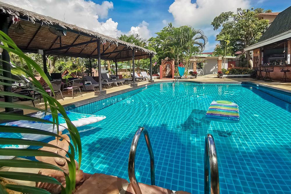 Outdoor swimming pool at Harmony Naturist Resort Phuket with sunbeds and tropical garden