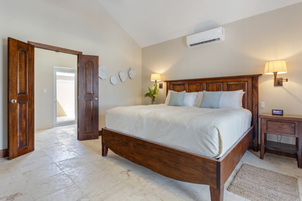 Primary bedroom in the Jellyfish Bungalow with king size bed, wood furnishings, ceiling fan, and private resort style ambiance during Belize Nude Takeover 2026