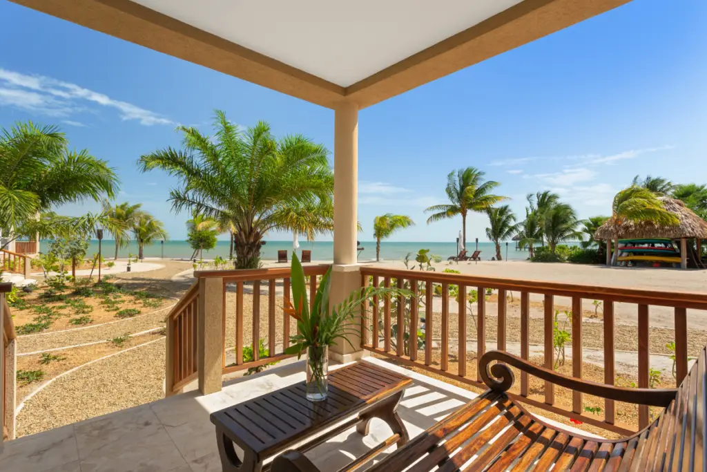 View from the Sand Dollar Bungalow overlooking Sirenian Bay resort beach, palm trees, recreational area and walkways during the Nude Takeover 2026 in Belize