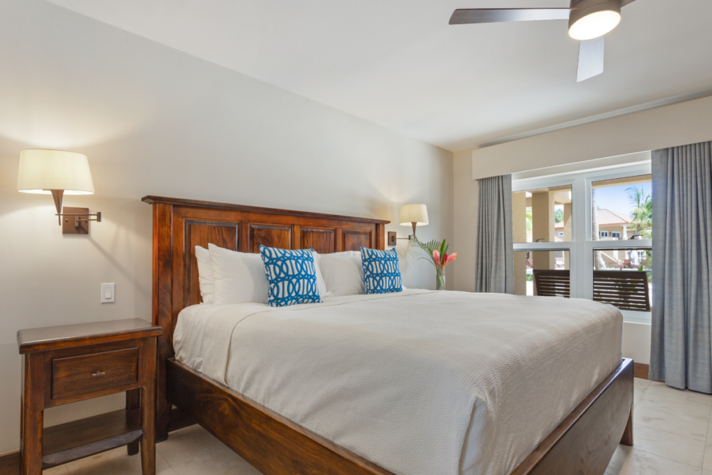 Primary bedroom in the Stingray Bungalow with king size bed, wood furnishings, ceiling fan, and private resort style ambiance during Belize Nude Takeover 2026