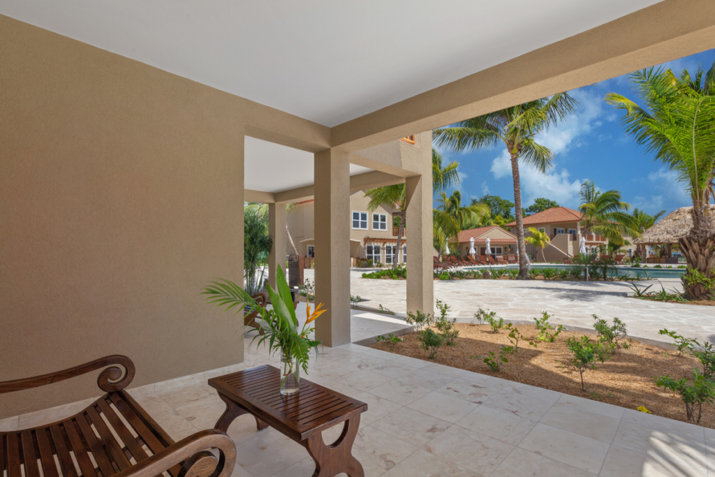 View from the Stingray Bungalow overlooking Sirenian Bay resort grounds, palm trees, and walkways during the Nude Takeover 2026 in Belize