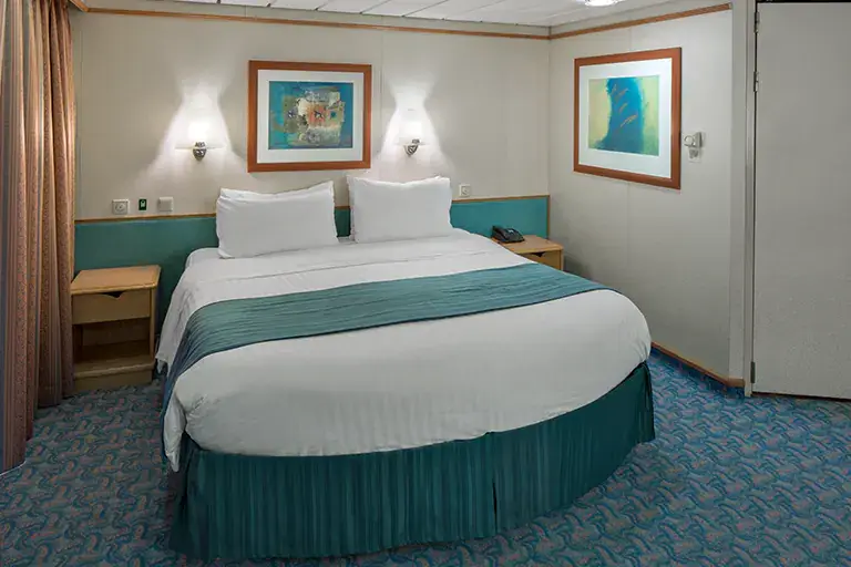 Junior suite bedroom with queen bed and seating area on Mariner of the Seas, Bliss Cruise February 2028 New Orleans adults only nude swinger cruise