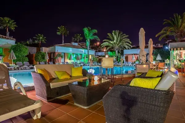 Nude resort Spain Canary Islands with illuminated swimming pool, outdoor lounge seating, and tropical gardens at night