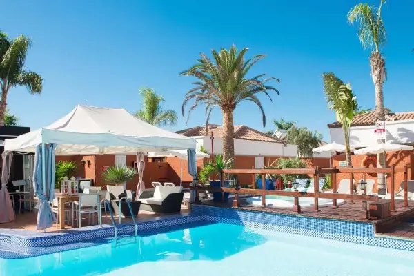 Nude resort Spain Canary Islands featuring a tropical pool area, sun loungers, palm trees, and relaxing outdoor gathering spaces