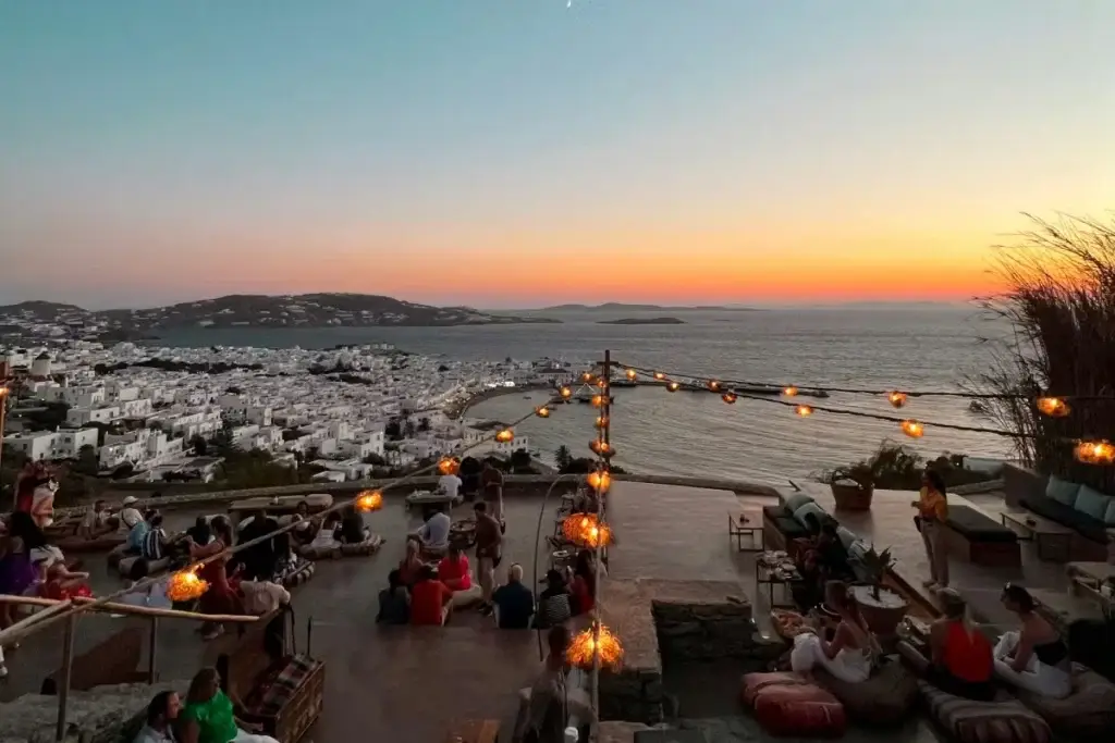 Sunset overlooking Mykonos, Greece, with waterfront lounges and nightlife, featured on an adults only lifestyle group trip aboard Virgin Voyages Scarlet Lady.