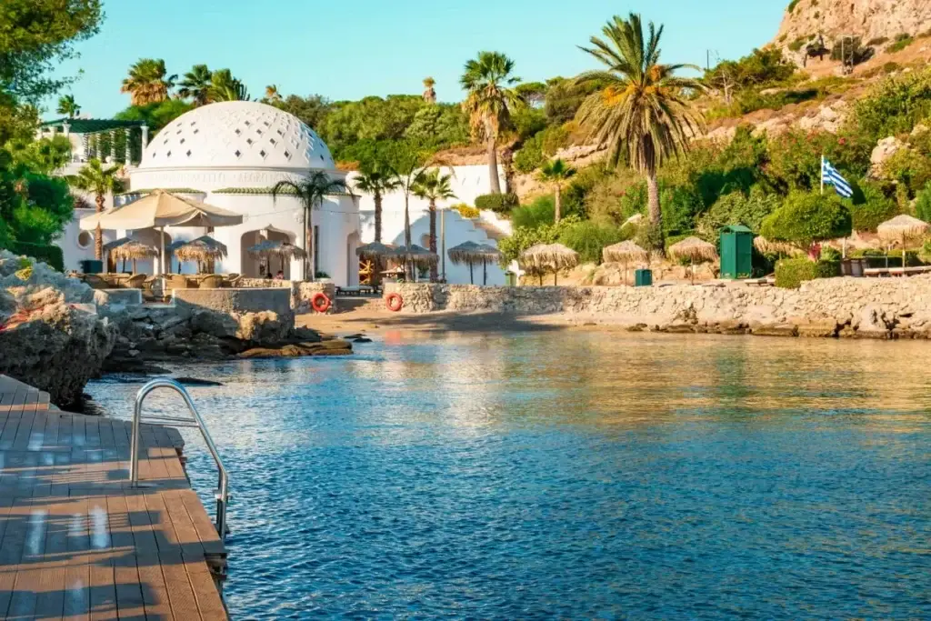 Scenic waterfront view of Rhodes, Greece, showcasing crystal clear waters and coastal beauty during an adults only lifestyle group trip aboard Virgin Voyages.